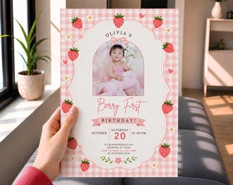 May include: A rectangular birthday invitation card featuring a pink and white gingham pattern background, decorated with strawberry and daisy illustrations. The center displays a photo of a child, the text Olivia's Berry First Birthday, and event details.