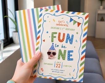 May include: A rectangular birthday invitation card with a colorful striped border. The text reads Let's celebrate Jackson's 1st Birthday FUN to be ONE, July 22, 3:00 PM, 123 Maple Street, Anytown, USA, RSVP to Alex 555-123-4567, featuring a baby in sunglasses.