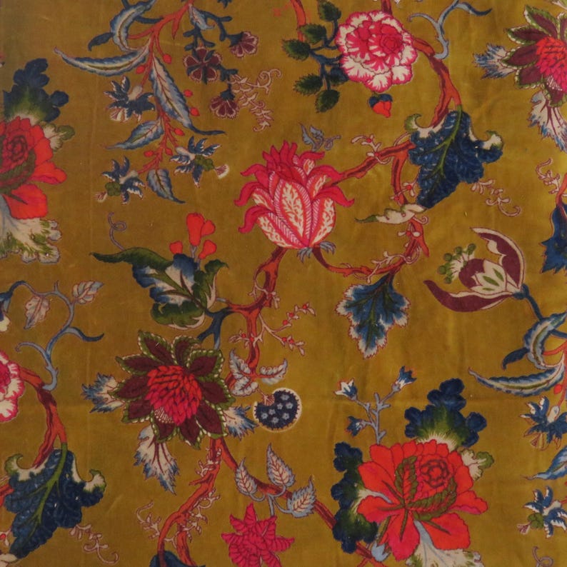 Puede incluir: Una tela de color amarillo mostaza con un patr&oacute;n floral repetitivo que presenta grandes flores en tonos rojo, rosa y morado oscuro, acentuadas por follaje azul oscuro y verde con intrincados detalles de l&iacute;neas blancas en el dise&ntilde;o.