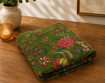 Puede incluir: Un textil verde plegado con un patrón floral repetitivo en tonos rojo, rosa, amarillo y azul. La tela muestra intrincados motivos botánicos que incluyen grandes flores, capullos más pequeños y enredaderas con hojas en toda la superficie.