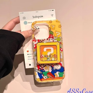 May include: Yellow phone case featuring a colorful Super Mario Bros. design. The case includes images of Mario, question mark blocks, and other iconic characters. The case is held in a person's hand, with the Instagram app visible in the background.