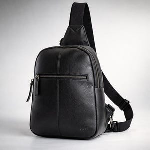 Puede incluir: Bandolera de cuero negro con acabado texturizado. Cuenta con un compartimento principal con cremallera, un bolsillo frontal con cremallera y una correa de hombro ajustable. La bolsa tiene el texto "MASTERLEATHERPK PREMIUM LEATHER GOODS" en la parte superior.