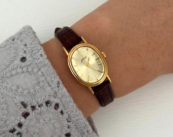 Orologio da donna con cinturino in pelle dorata e marrone, classico al quarzo, minimalista.