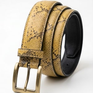 May include: A yellow and brown snakeskin-patterned belt with a rectangular brass buckle. The belt is rolled up, showcasing the textured pattern and the black leather interior. The buckle is a classic design, adding a touch of sophistication.