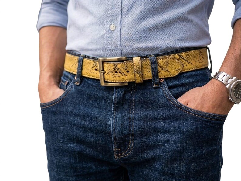 K&ouml;nnte beinhalten: Ein gelber G&uuml;rtel mit Schlangenmuster und einer rechteckigen Messingschnalle. Der G&uuml;rtel wird mit einer blauen Jeans und einem hellblauen Hemd getragen. Die Breite des G&uuml;rtels betr&auml;gt ca. 3,8 cm.