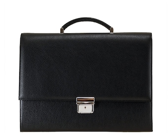 May include: A black leather briefcase with a textured finish. It features a silver clasp and a curved handle. The design is simple and professional, suitable for carrying documents and other essentials.