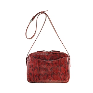 Peut inclure: Un sac à bandoulière en cuir de serpent rouge avec une longue bandoulière réglable.