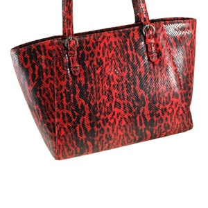 Könnte beinhalten: Eine rote und schwarze Schlangenleder-Tragetasche mit zwei Henkeln oben und einem Reißverschluss.