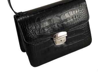 May include: A black leather handbag with a crocodile-embossed pattern and a silver clasp.