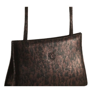 Könnte beinhalten: Eine braune Ledertasche mit Schlangenhautmuster und einem goldfarbenen Logo.