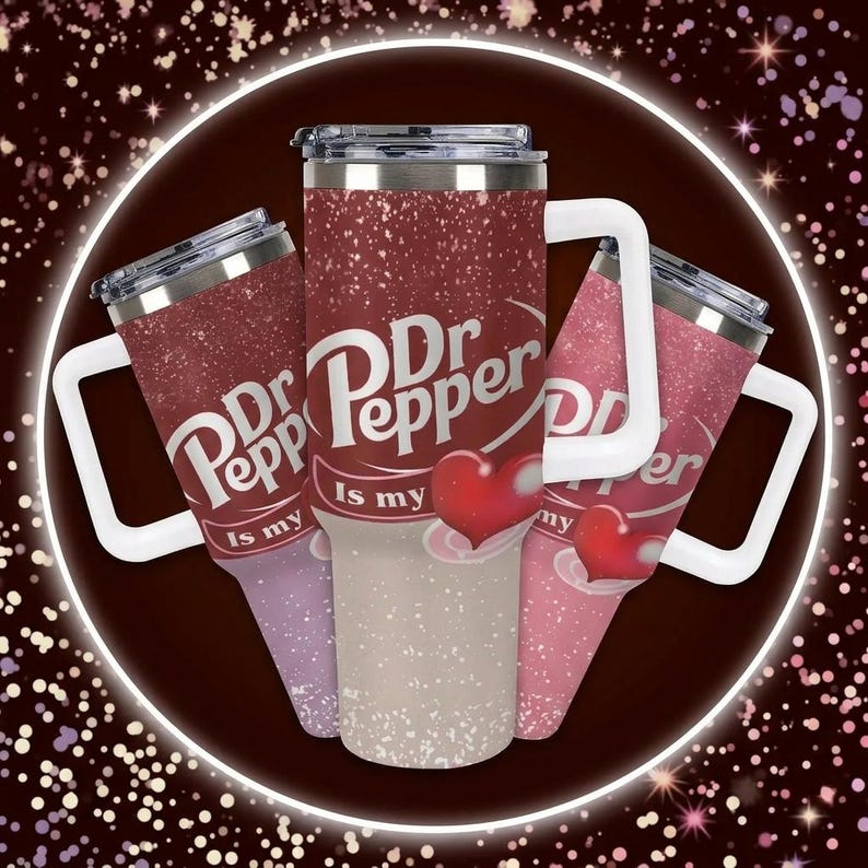 Puede incluir: Tres vasos aislados con el logotipo de Dr. Pepper y la frase "Is my" en blanco. Los vasos tienen un dise&ntilde;o de purpurina roja con un gr&aacute;fico de coraz&oacute;n. Cada vaso tiene un asa blanca y una tapa plateada.
