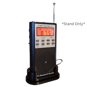 Könnte beinhalten: Schwarze P-SB7T Spirit Box mit roter Digitalanzeige, die 87,5 FM anzeigt. Das Gerät hat eine silberne Antenne und ist auf einem schwarzen Ständer montiert. Der Text "TC Research Device" ist auf dem Ständer sichtbar.