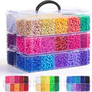 May include: A clear plastic bead organizer with a black handle, filled with various colors of beads. The organizer has multiple compartments, each holding a different color, including pink, yellow, blue, and purple. Additional smaller organizers are visible below, also filled with beads.