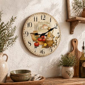 May include: A round wall clock with a vintage design. The clock face features a painted illustration of a still life with tomatoes, olive oil, and the text "Huile d'Olive". Black clock hands point to the time. The clock is mounted on a textured white wall.
