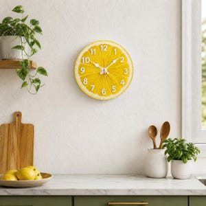 Op de afbeelding: Een ronde wandklok met een heldergele citroen schijf ontwerp. De klok heeft witte cijfers en wijzers en is aan een witte muur bevestigd. De klok heeft een diameter van ongeveer 30 cm, geschikt voor een keuken of eetkamer.