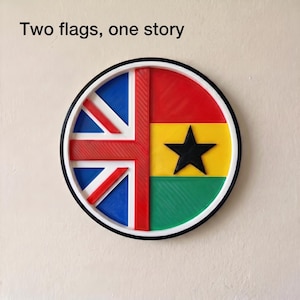 May include: A round decorative piece featuring the flags of the United Kingdom and Ghana. The UK flag is on the left, and the Ghanaian flag is on the right. The text "Two flags, one story" is above the flags.