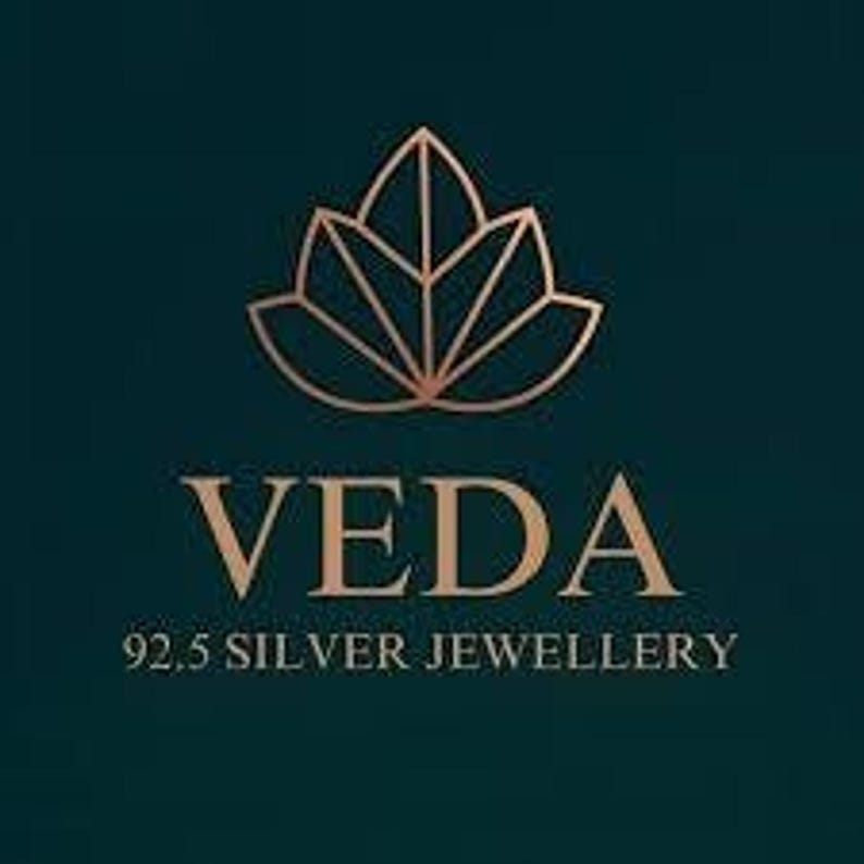 A brand logo featuring a stylized geometric lotus flower in gold above the text Veda 92.5 Silver Jewellery.