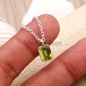 May include: A silver necklace featuring a rectangular, light green gemstone pendant. The pendant is set in a silver frame and hangs from a delicate silver chain. The necklace is displayed against a neutral background.