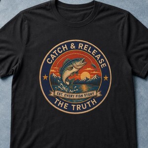 May include: A black short-sleeved t-shirt featuring a circular graphic with a jumping fish, mountains, and a sunset. The text reads CATCH & RELEASE, EST. EVERY FISH STORY, and THE TRUTH in a vintage-inspired design with blue, orange, and cream colours.