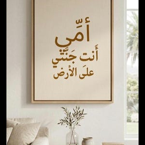 Può includere: Una stampa artistica su tela incorniciata con calligrafia araba dorata. Il testo recita: "Madre, sei il mio paradiso in terra". L'opera d'arte è esposta in un soggiorno.