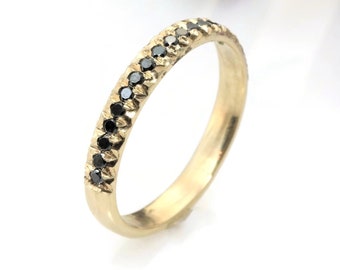 May include: A gold band ring with a row of black diamonds.