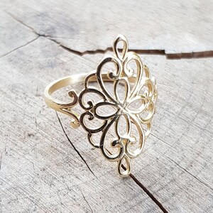 K&ouml;nnte beinhalten: Ein goldener Filigranring mit einem zarten, filigranen Design. Der Ring ist diamantf&ouml;rmig und hat ein florales Muster.