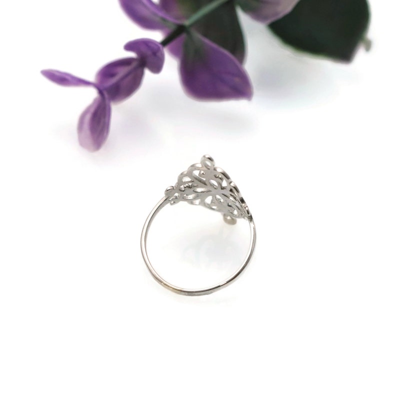 K&ouml;nnte beinhalten: Ein silberner Filigranring mit einem zarten, filigranen Design. Der Ring ist an einer Seite offen und hat ein schlichtes Band.