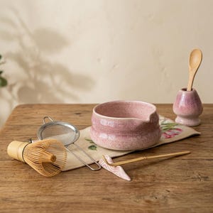 Peut inclure: Un ensemble à thé matcha avec un bol en céramique rose, un fouet, une passoire, une cuillère et un support. L'ensemble comprend un fouet en bambou, une petite cuillère en bois et un repose-cuillère en céramique.