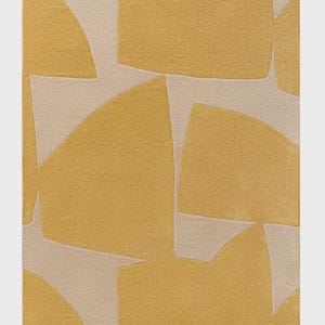 May include: A rectangular rug with an abstract design. The rug features a pattern of geometric shapes in shades of yellow and beige. The shapes include squares, rectangles, and curved forms, creating a modern aesthetic.