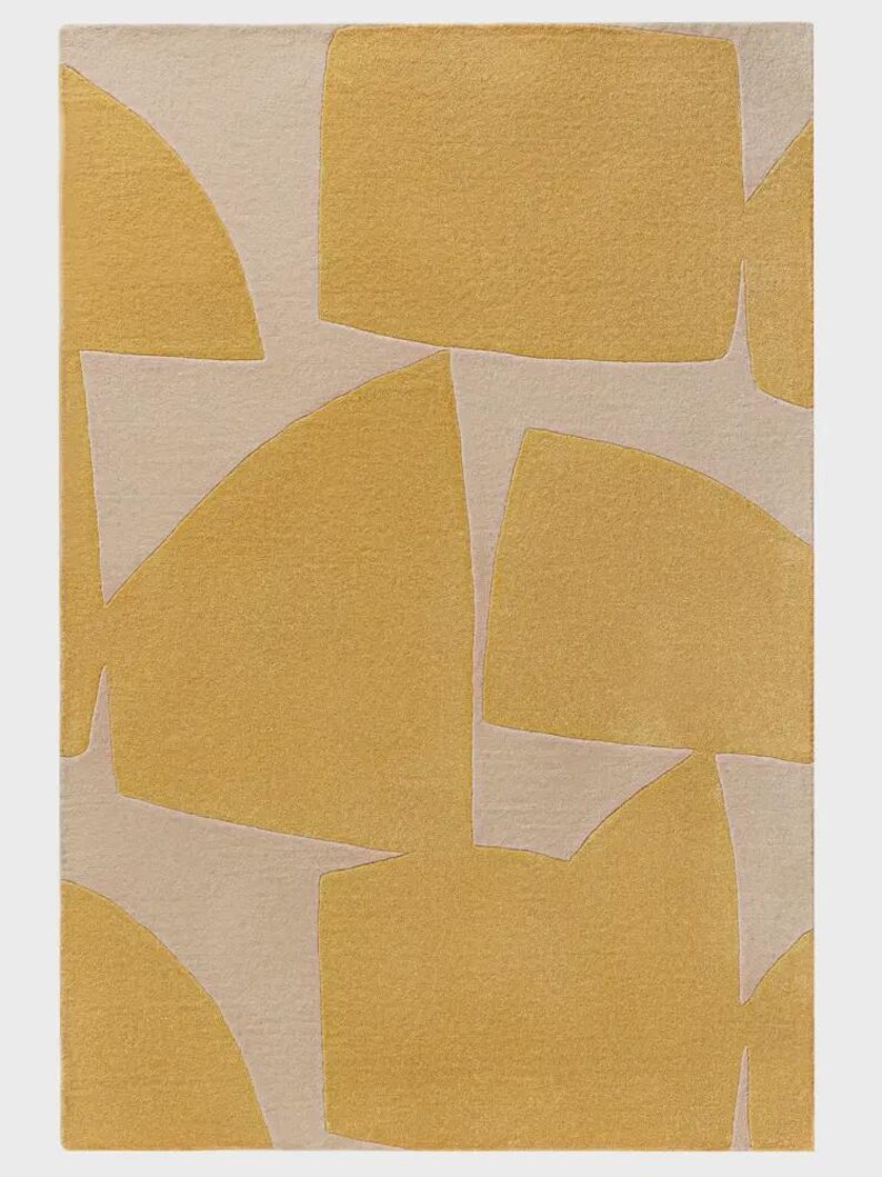 May include: A rectangular rug with an abstract design. The rug features a pattern of geometric shapes in shades of yellow and beige. The shapes include squares, rectangles, and curved forms, creating a modern aesthetic.