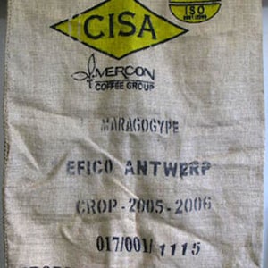 Könnte beinhalten: Ein Kaffeesack aus Jute mit aufgedrucktem Text und Logos. Der Text enthält "CISA", "MERCON COFFEE GROUP", "MARAGOGYPE", "EFICO ANTWERP", "CROP-2005-2006" und "PRODUCT OF NICARAGUA". Ein gelbes Diamant- und Oval-Logo ist ebenfalls sichtbar.