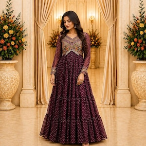 May include: A floor-length deep purple dress with long sleeves and a tiered skirt. The bodice features a V-neckline with intricate multi-colored embroidery and metallic accents. The fabric has a subtle repeating pattern throughout the garment.