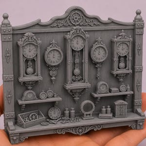 May include: A gray miniature wall display featuring a collection of various clocks, including tall grandfather clocks, round wall clocks, and small shelf clocks, arranged on a wooden-textured panel with shelves, gears, and small storage containers.