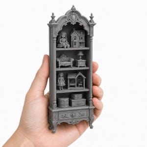 Puede incluir: Una vitrina miniatura gris con una parte superior arqueada y tallas ornamentadas. Los cuatro estantes contienen figuras diminutas, incluyendo dos muñecas, dos casas en miniatura, un sofá, una lámpara, una mesa auxiliar y dos cajas pequeñas.