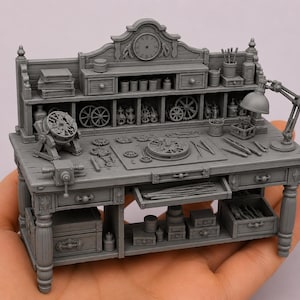 May include: A miniature gray resin workbench featuring a clock face on the backboard, multiple drawers, shelves filled with tiny gears, tools, and containers. The detailed model includes a desk lamp, a small vise, and various clockmaking components.