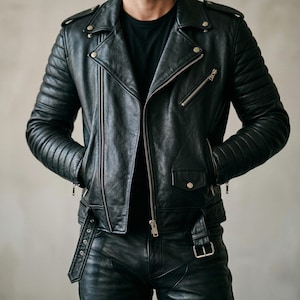 Puede incluir: Chaqueta de cuero negra de estilo motero con detalles acolchados en hombros y mangas, cuello con solapas y múltiples bolsillos con cremallera. La chaqueta tiene cierre de cremallera diagonal y cinturón en la cintura. Se combina con pantalón negro y camiseta negra.