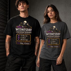 以下が含まれることがあります： 黒とグレーのTシャツを着た2人。シャツには「WEDNESDAY」、「CHECKPOINT REACHED」、「AUTOSAVE COMPLETE」という文字が入ったグラフィックが描かれています。グラフィックには「+5 Morale」、「+1 Hope」、「-10 Energy」、「+1 Day Closer」も含まれています。