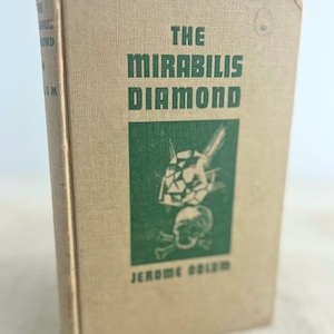 May include: A hardcover book titled The Mirabilis Diamond by Jerome Odlum with a tan fabric cover. The front features dark green text and a central green rectangular graphic depicting a faceted diamond above a skull and crossbones illustration.