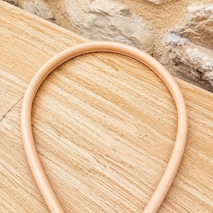 Pu&ograve; includere: Un manico per borsa in pelle color beige chiaro di forma arrotondata, dotato di chiusure a moschettone in metallo dorato su entrambe le estremit&agrave;. Il manico presenta cuciture visibili ed &egrave; progettato per essere fissato a una borsa.