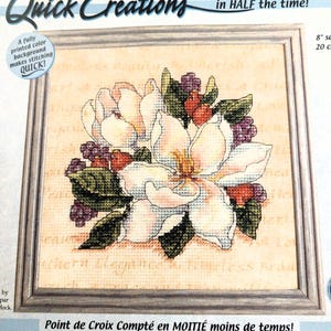 May include: A framed counted cross stitch kit featuring a magnolia flower design. The kit includes cotton thread, an 8-inch square printed Aida cloth, a needle, and instructions. The text on the packaging reads "Quick Creations" and "Cherished Magnolia."