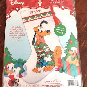 May include: A Disney cross-stitch stocking kit featuring Pluto in a Christmas sweater. The kit includes thread, Aida fabric, felt, needle, and instructions. The stocking is 10 inches (25.4 cm) long and has the name "EMMA" stitched on it.