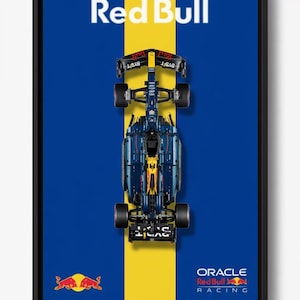 May include: Framed print featuring a top-down view of a Red Bull Racing Formula 1 car. The car is centered on a yellow stripe against a blue background. The Red Bull logo and Oracle branding are visible.