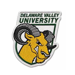 Könnte beinhalten: Gestickter Aufnäher mit dem Logo der Delaware Valley University. Der Aufnäher hat einen weißen Rand mit grüner Umrandung. Das Logo zeigt einen gelben Widderkopf mit grauen Hörnern und die Worte "DELAWARE VALLEY UNIVERSITY" in Grün.