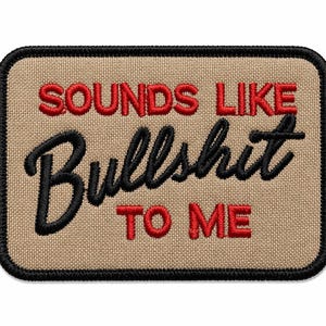 Puede incluir: Parche bordado con la frase "SOUNDS LIKE BULLSHIT TO ME". El texto es en rojo y negro, con una fuente cursiva para "Bullshit". El parche tiene un fondo beige y un borde negro.