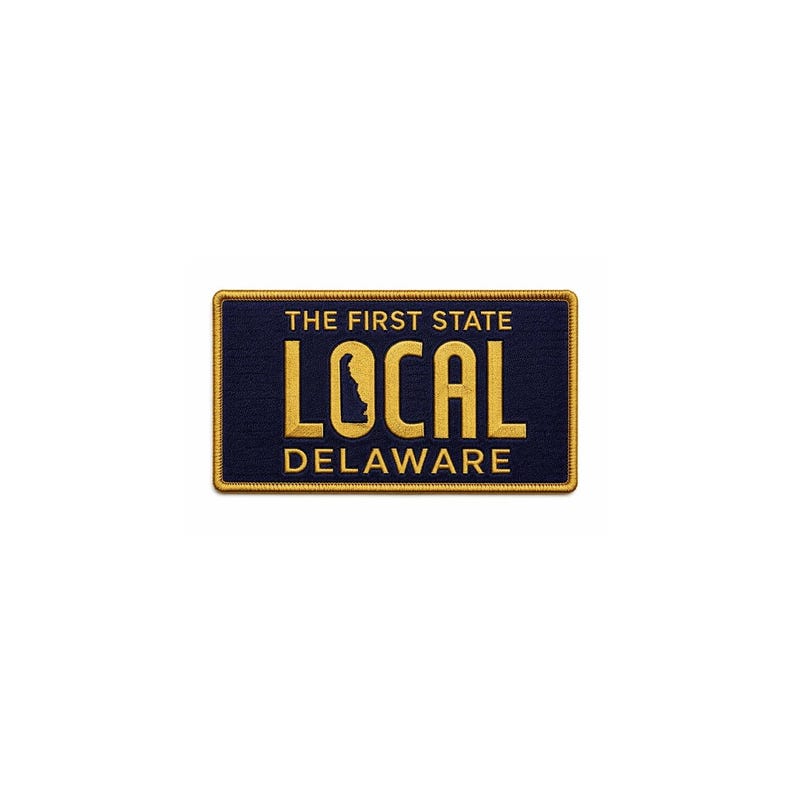 Peut inclure: Un &eacute;cusson rectangulaire avec un fond bleu marine et du texte brod&eacute; en or. Le texte se lit "THE FIRST STATE LOCAL DELAWARE" avec un contour dor&eacute; de l'&Eacute;tat du Delaware. L'&eacute;cusson a une bordure dor&eacute;e.