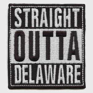 Op de afbeelding: Geborduurde patch met de tekst "STRAIGHT OUTTA DELAWARE" in wit en zwart. De patch is rechthoekig met een zwarte rand en witte stiksels. De tekst is in een vetgedrukte, schreefloze lettertype.