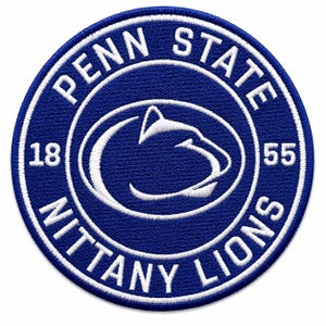 Pode incluir: Um patch circular bordado em azul marinho com letras e detalhes brancos. O texto "PENN STATE NITTY LIONS" é bordado ao redor da borda, com "PENN STATE" no topo. Um logotipo de cabeça de leão branco está no centro, com os números "18" e "55" em ambos os lados.