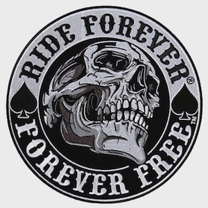 May include: A circular patch with a skull graphic, surrounded by the words "RIDE FOREVER FOREVER FREE" in white lettering. The skull is detailed in shades of gray and black, with two black spade symbols on either side.