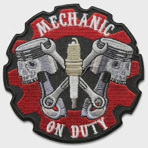 May include: Embroidered patch with a mechanic theme. The design features crossed wrenches, a spark plug, and two piston heads, all set against a red gear and a black background. The words "MECHANIC ON DUTY" are prominently displayed.