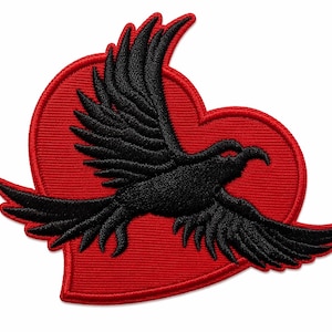 Peut inclure: Écusson brodé représentant un oiseau noir en vol, sur un fond rouge en forme de cœur. L'oiseau présente des motifs détaillés d'ailes et de plumes. L'écusson est probablement destiné aux vêtements ou aux accessoires.